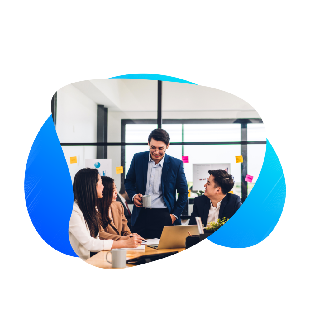 Three individuals in a bright office space engaged in a discussion with laptops and documents on the table.